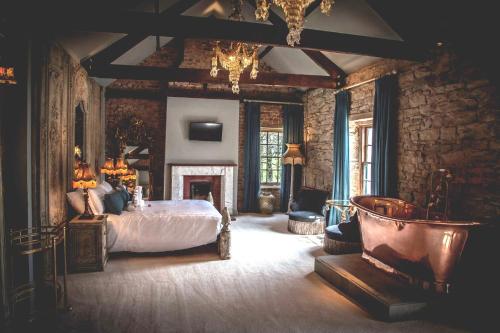 a large bedroom with a bed and a fireplace at Le Petit Chateau & William de Percy in Otterburn