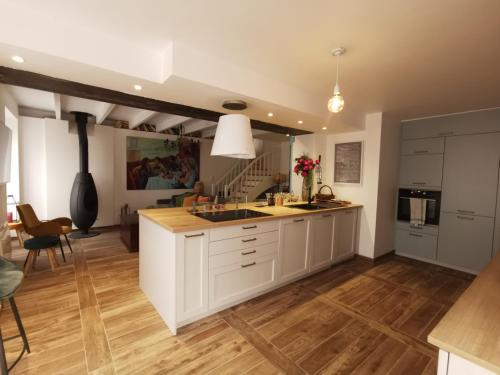 uma cozinha com armários brancos e piso em madeira em Les 3 Cheminées em Granville