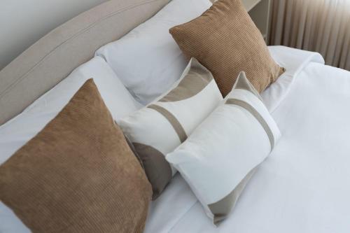 a bed with white pillows and brown pillows at O&O Group - SeaFront Luxurious 3 BR Apartment in Bat Yam