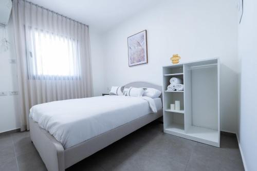 a white bedroom with a bed and a window at O&O Group - SeaFront Luxurious 3 BR Apartment in Bat Yam