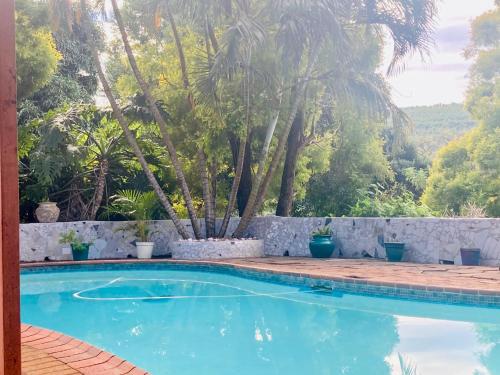 a swimming pool with a stone wall and trees at Su Casa Chase Valley in Pietermaritzburg