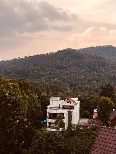 a large white building in front of a mountain at Forest View Resort in Yercaud