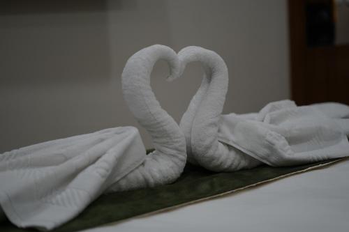 duas toalhas em forma de cisnes numa cama em HOTEL STATURE INN em Kevadia