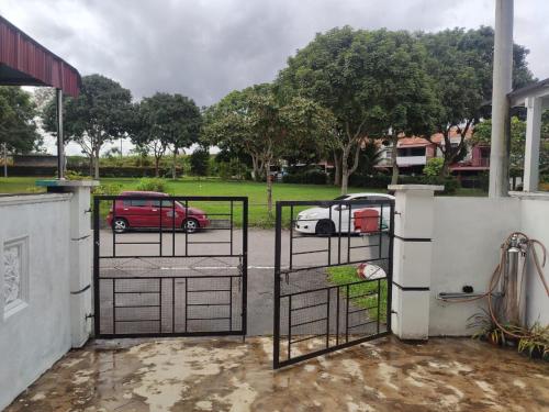 a gate with a car parked in a parking lot at Rumah teres 2 tingkat & 3 bilik in Pasir Gudang