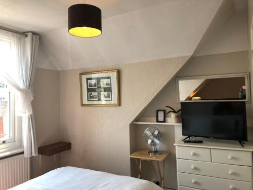 a bedroom with a bed and a flat screen tv at Carena House in Canterbury
