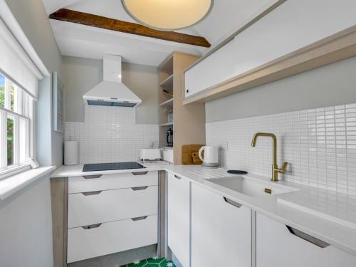 a kitchen with white cabinets and a sink at Pass the Keys Stunning Georgian Cottage In The City in Canterbury