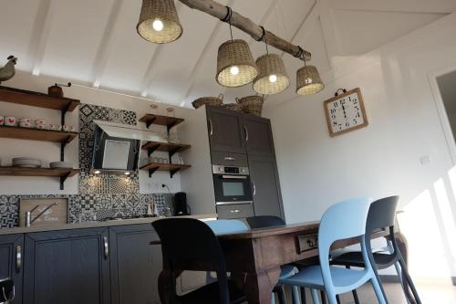 eine Küche mit einem Tisch, Stühlen und einigen Lampen in der Unterkunft Le GITE DU VILLAGE in Franleu