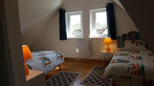 ein Schlafzimmer mit zwei Betten und zwei Fenstern in der Unterkunft Le GITE DU VILLAGE in Franleu