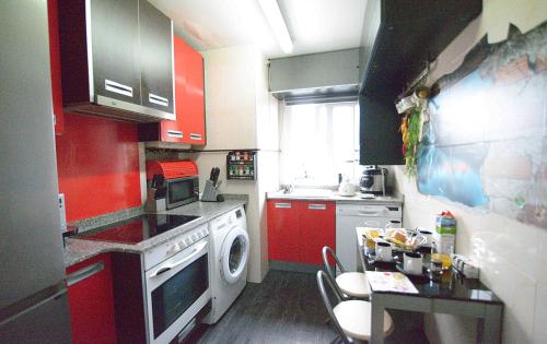 サンタンデールにあるEl apartamento de Emiliaのキッチン(赤いキャビネット、洗濯機付)