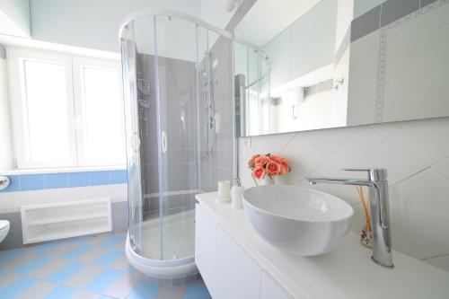 y baño blanco con lavabo y ducha. en Don Raffaè - Luxury Apartment, en Isquia