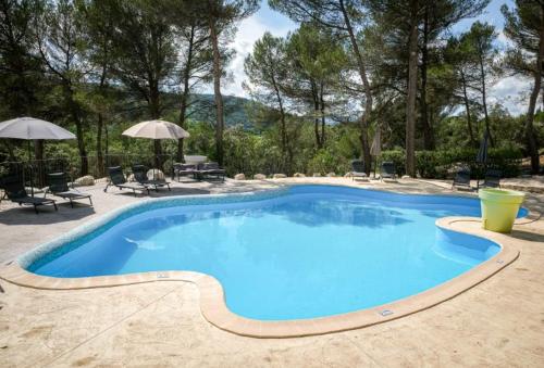 une grande piscine bleue avec des chaises et des parasols dans l'établissement Hôtel La Pinède, à Saint-Marcellin-lès-Vaison