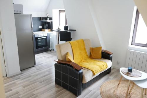 uma sala de estar com um sofá com um cobertor amarelo em La Perle em Montargis