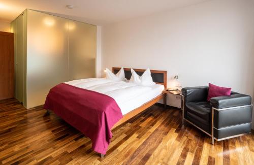 a bedroom with a large bed and a black leather chair at Prümer Gang Restaurant & Hotel in Bad Neuenahr-Ahrweiler
