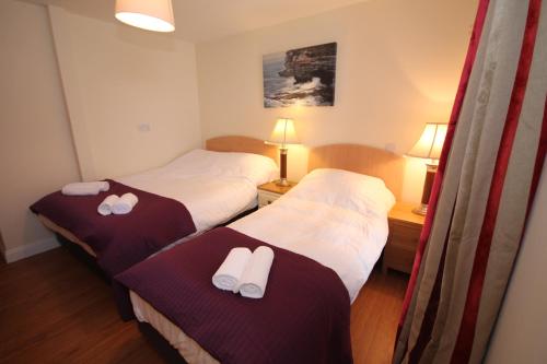 two beds in a hotel room with white towels on them at Marine Apartment in Aberystwyth