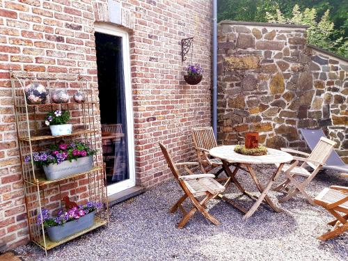a patio with a table and chairs next to a brick wall at La Maison des Senteurs in Francorchamps