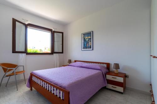 a bedroom with a bed and a window and a chair at Villa Dalila by BarbarHouse in Torre Inserraglio