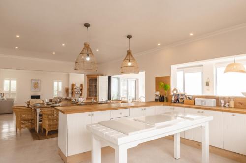 eine große Küche mit weißen Schränken und einem Tisch in der Unterkunft Yzer Beach House in Yzerfontein