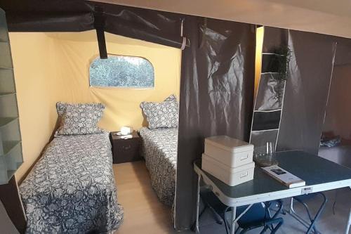 ein kleines Schlafzimmer mit einem Bett und einem Schreibtisch in der Unterkunft Logement Lodge au cœur de la Manade in Aigues-Mortes