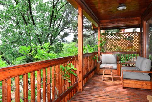 a wooden porch with two chairs on it with trees at NIMA Navacerrada in Navacerrada