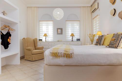 a white bedroom with a large bed and a chair at Naxos Beach Front Villa ''Moments'' in Ambrami