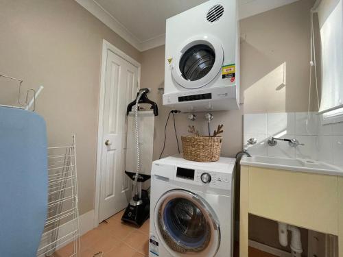 a washing machine in a kitchen with a microwave at Blue Haven Retreat - Glenmore Park Pool Home in Glenmore Park