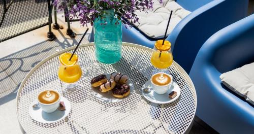 a table with two cups of coffee and donuts on it at Garni Hotel Mint in Belgrade