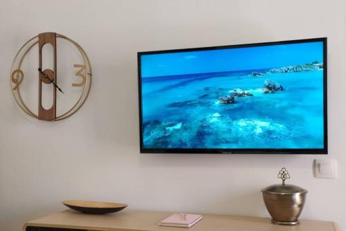 a flat screen tv hanging on a wall with a clock at Xenofon's cozy apartment in Corfu
