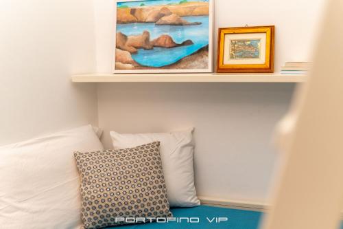 a shelf above a bed with a pillow and paintings at Papù 2 by PortofinoVip in Portofino