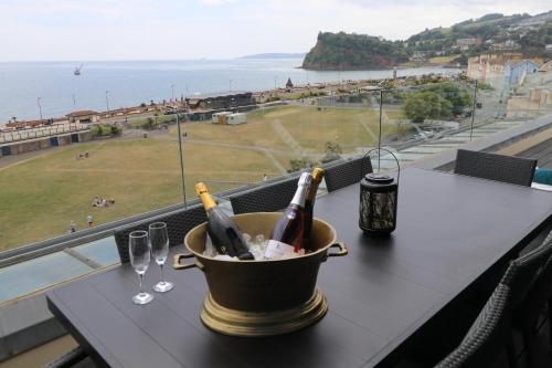 a bucket of wine bottles and glasses on a table at Riviera Apartments - Five Stylish Penthouse Apartments with Unrivalled Sea Views of Teignmouth, Shaldon, The Jurassic Coastline & The Teign Estuary in Teignmouth