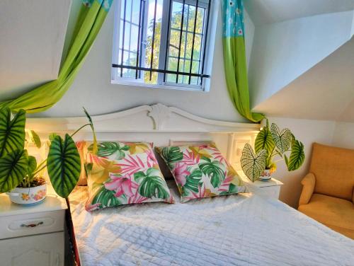 Un dormitorio con una cama con almohadas de colores y una ventana en Chambre comte de Saint-Exupéry, en Cap Malheureux