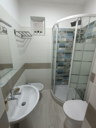 a white bathroom with a sink and a shower at Oltremare in Diamante