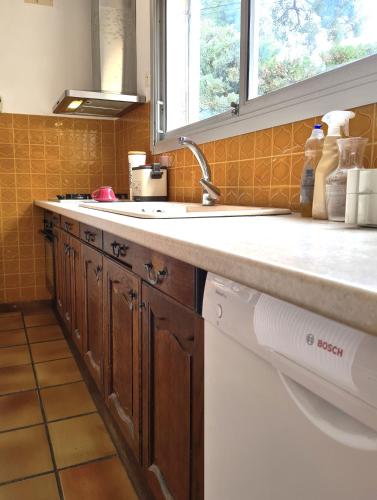 un comptoir de cuisine avec un évier et une fenêtre dans l'établissement Villa Rima, bas de villa vue mer avec piscine à 200m des plages, à La Ciotat