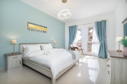 a bedroom with a large white bed with blue walls at Sensational 1BR in Bab Al Bahar with Beach Access in Ras al Khaimah