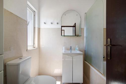 bagno con servizi igienici, lavandino e specchio di Casa Kuito a Estói