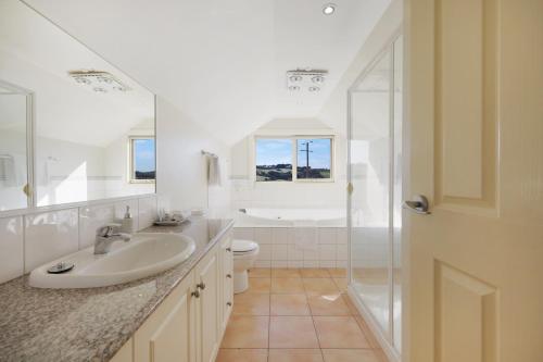 a white bathroom with a sink and a shower at Logans Beach Apartments - The Loft in Warrnambool