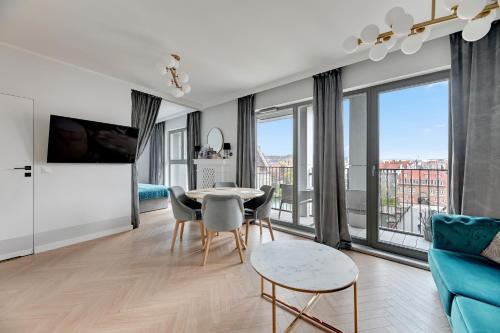 a living room with a table and chairs and windows at GRANO APARTMENTS Gdańsk Old Town SPA & Wellness - GRANO APARTMENTS Gdańsk Residence SPA & Wellness in Gdańsk