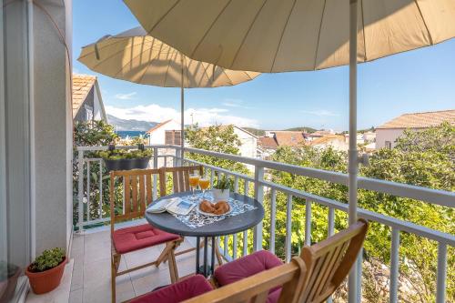 een balkon met een tafel en stoelen en een parasol bij Apartments Karisima in Korčula