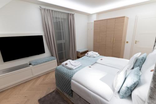 a bedroom with a white bed and a flat screen tv at SCHLOSSRESIDENZ - Boutique Apartments & Hotel Suiten in Schloß Ricklingen