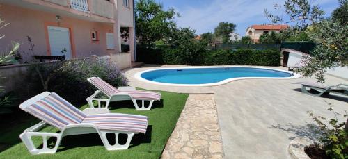 twee stoelen en een zwembad in de tuin bij Relax to the max with the sea view in Medulin