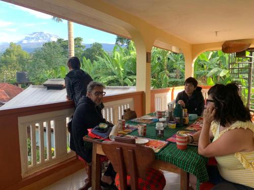 a group of people sitting at a table on a porch at Shimbwe Meadows Home in Moshi