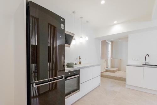 a kitchen with a black refrigerator and white cabinets at Gemela AllstarBoutique in Aegina A in Aegina Town