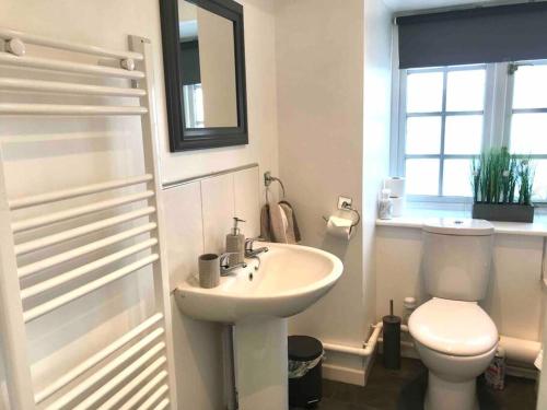 a white bathroom with a toilet and a sink at Great location very spacious. Sea and castle view in Marazion