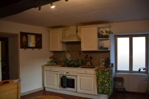 une cuisine avec des armoires blanches et une cuisinière dans l'établissement La Petite Ferme, à Montreuil-Bellay