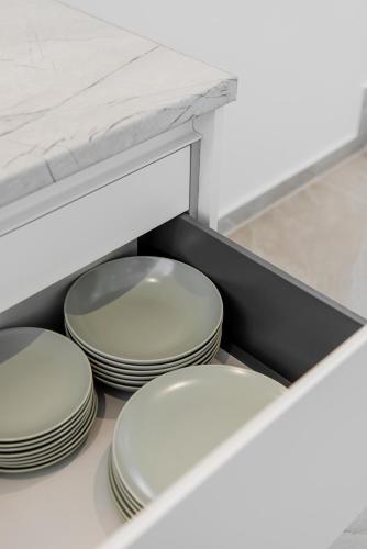 four white plates in a drawer in a kitchen at Gemela AllstarBoutique in Aegina A in Aegina Town