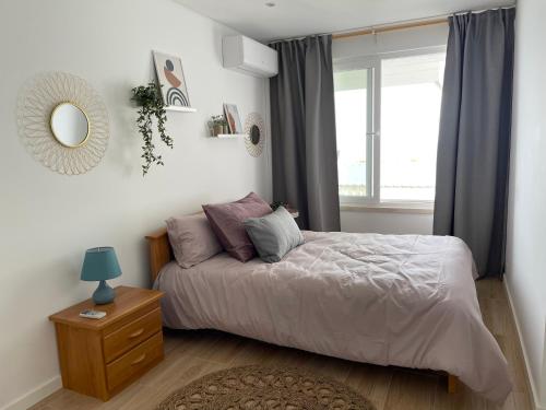 een slaapkamer met een bed met een spiegel en een raam bij Sesimbra Balcony in Sesimbra