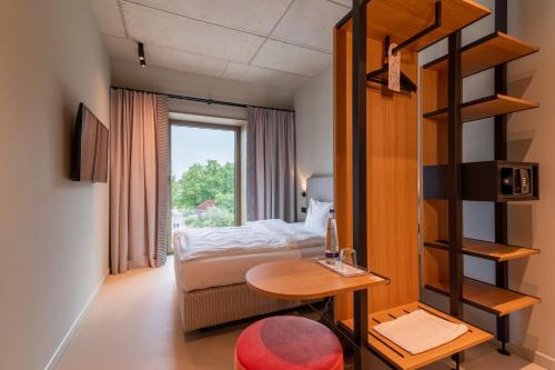a small room with a bed and a table and a window at MIANO Hotel & Bar in Munich