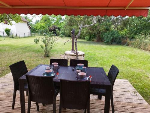 une table et des chaises noires sur une terrasse en bois dans l'établissement Maison de campagne avec terrain, à Vallon-en-Sully