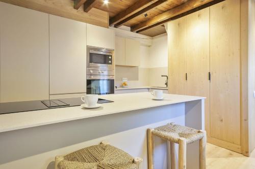 a kitchen with white cabinets and a stove top oven at Luderna - Dúplex Aiguamog in Arties