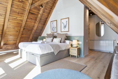 a bedroom with a large bed and a wooden ceiling at Luderna - Dúplex Aiguamog in Arties