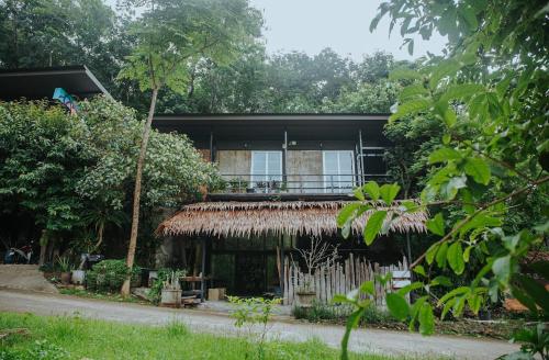 uma casa com telhado de palha numa floresta em ลอดจ์พังงา บูทีค em Phangnga